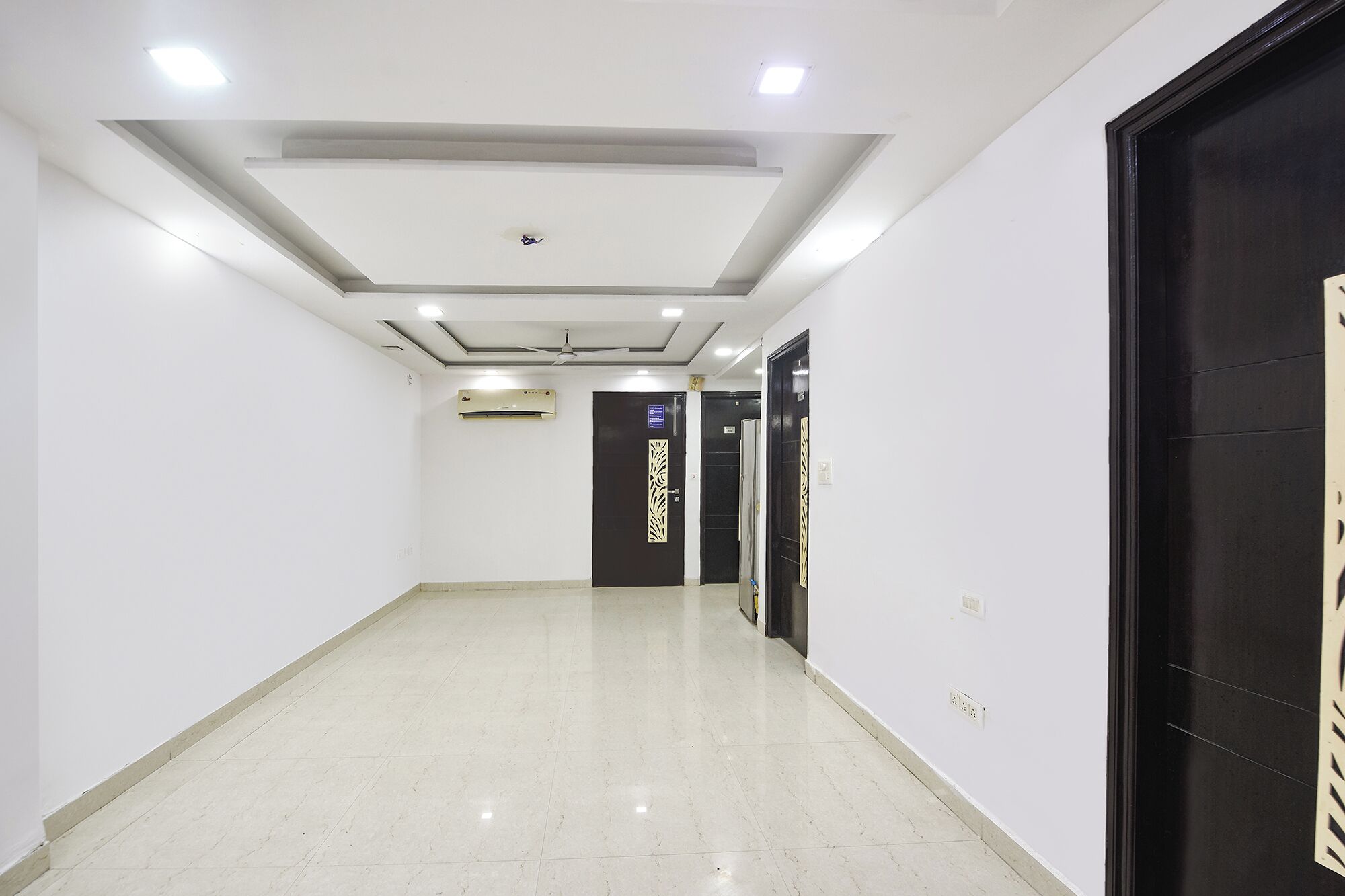 A clean, well-lit hallway with a tiled floor, a ceiling fan, and an air conditioning unit.