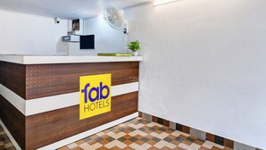 A reception desk with a wooden finish, a sign reading "fab hotels," and a small plant on top. - Fabhotel Vedsri (Kolkata)