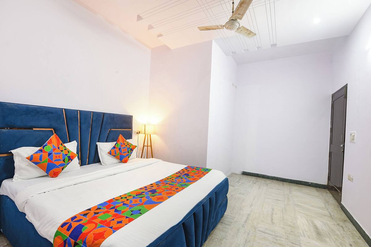Una habitación de hotel con una cama grande, un ventilador de techo y una lámpara.