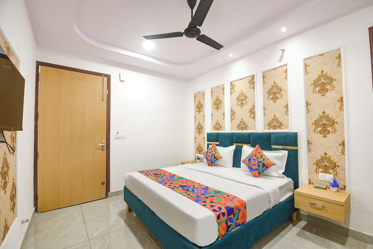 A bedroom with a bed, a nightstand, a ceiling fan, and patterned wallpaper.