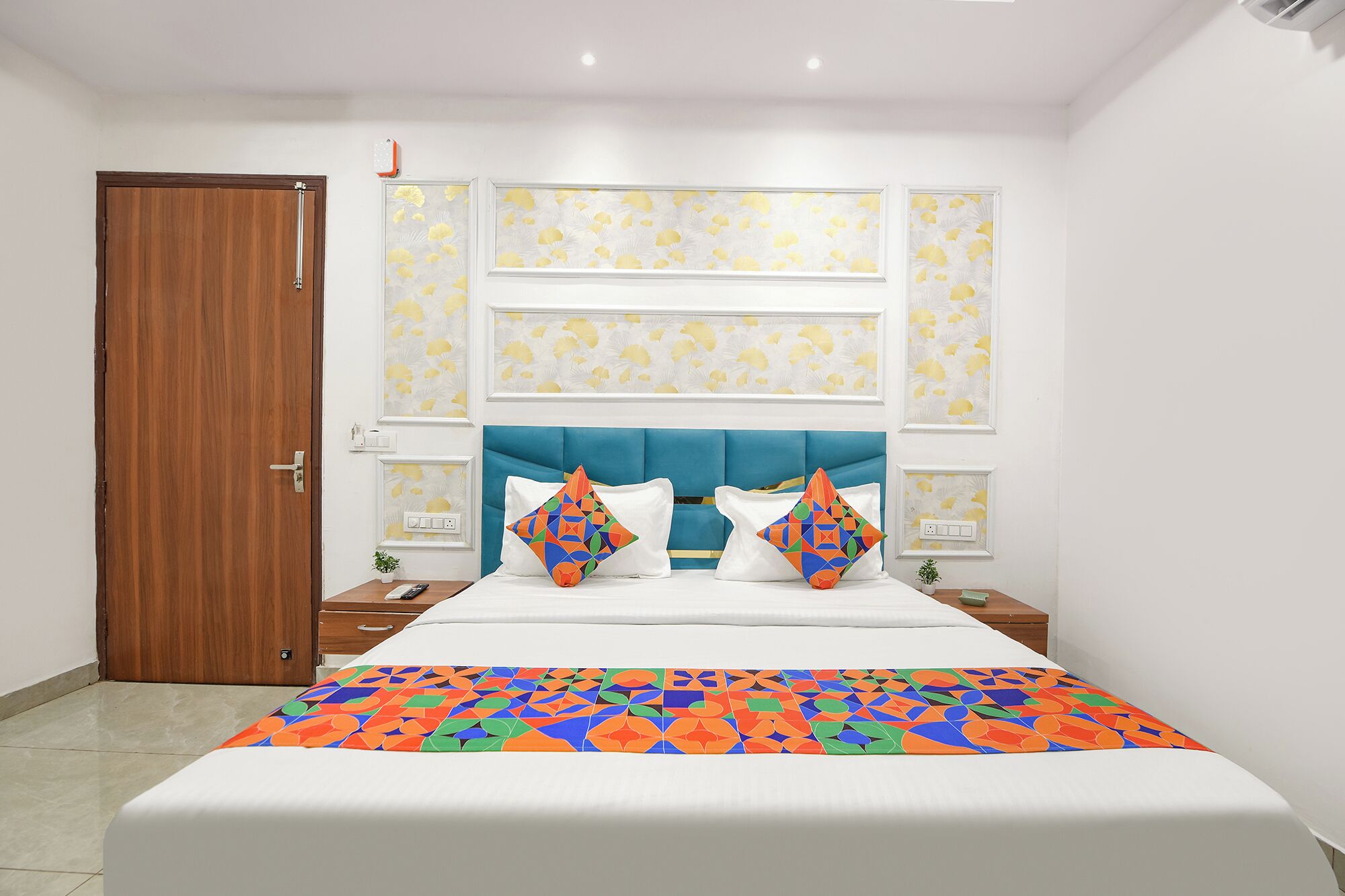 A bedroom with a large bed, a blue headboard, and a floral-patterned wall.