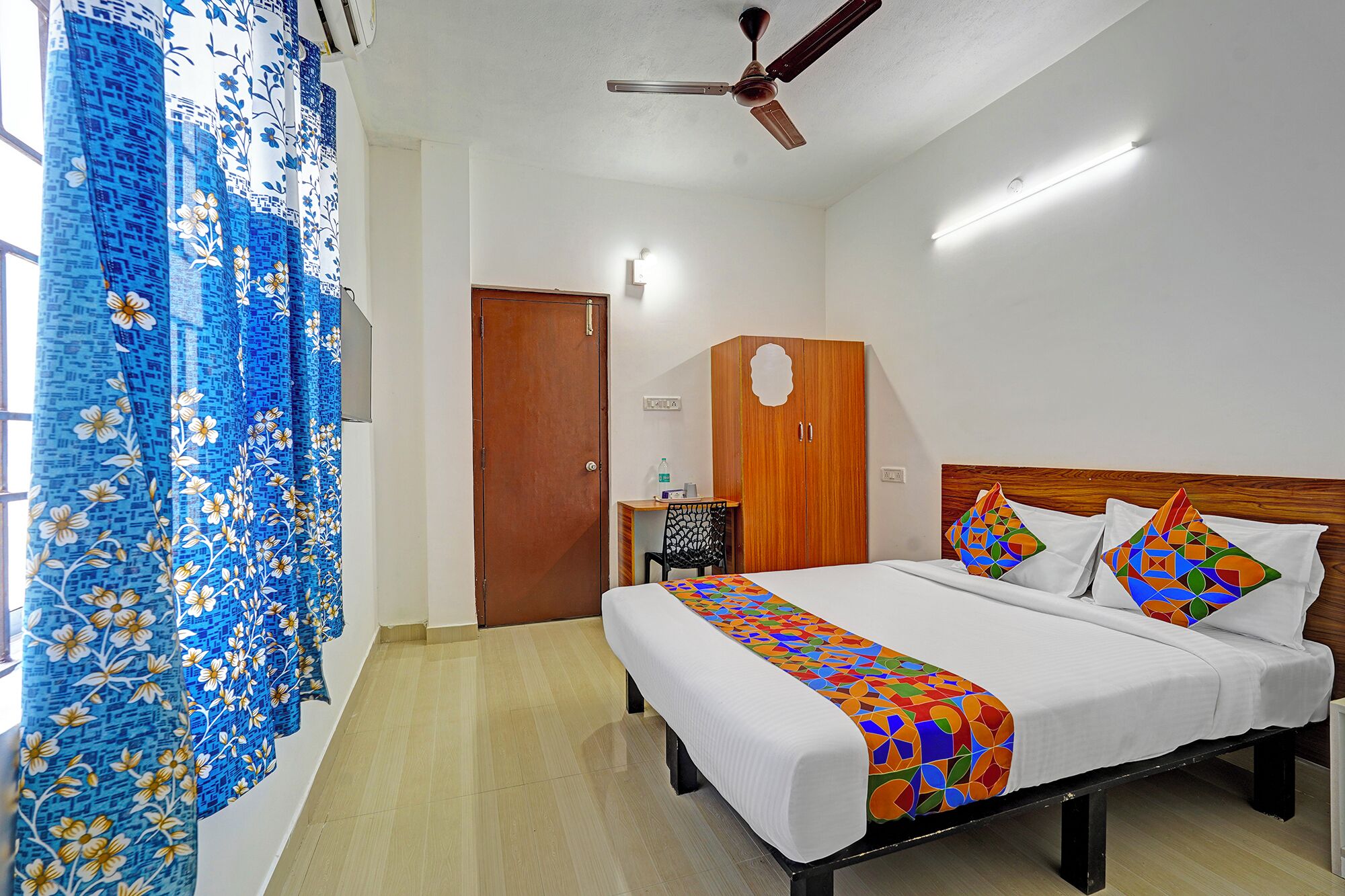 Une chambre d’hôtel avec un lit, une armoire, un bureau et une chaise.