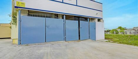 A building with a security sign, a gated entrance, and a clear sky.