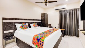 A modern hotel room with a large bed, a ceiling fan, an air conditioning unit, a TV, and a desk with a chair. - Fabhotel Sri Lakshmi Sea Grand (Visakhapatnam)