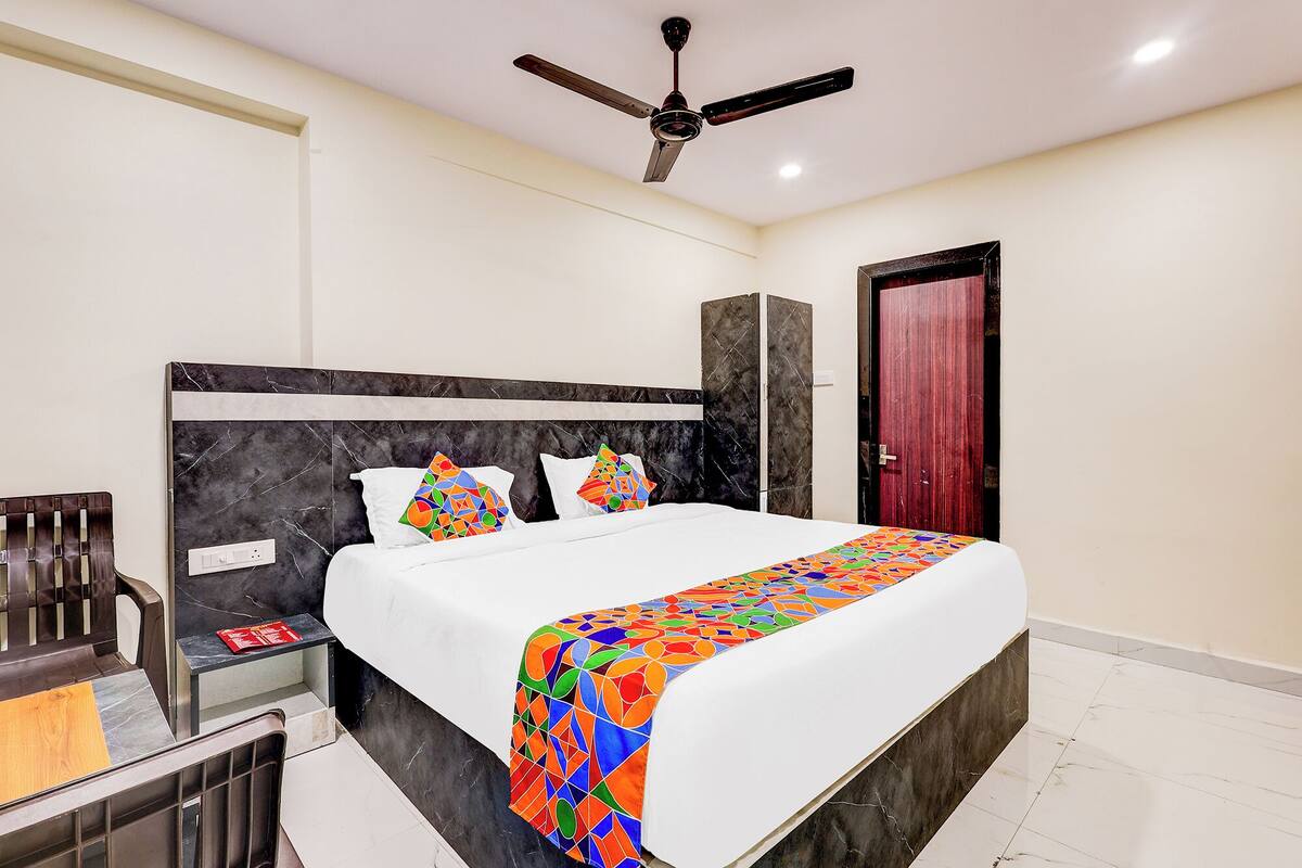 A bedroom with a bed, a ceiling fan, a wardrobe, and a door.