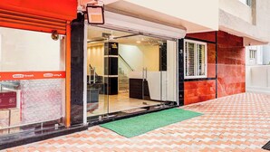 A hotel entrance with a glass door, a staircase inside, and a red and white facade. - Fabhotel Sri Lakshmi Sea Grand (Visakhapatnam)
