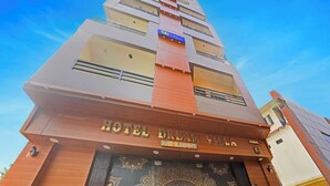 Un hôtel à plusieurs étages, reconnaissable à son grand panneau « Hotel Dream Villa », qui présente un design moderne aux couleurs beiges et brunes.