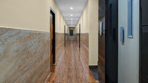 A corridor with tiled walls and a wooden floor, leading to doors with handles. - FabHotel Star Light B - Nr. Rushikonda (Visakhapatnam)