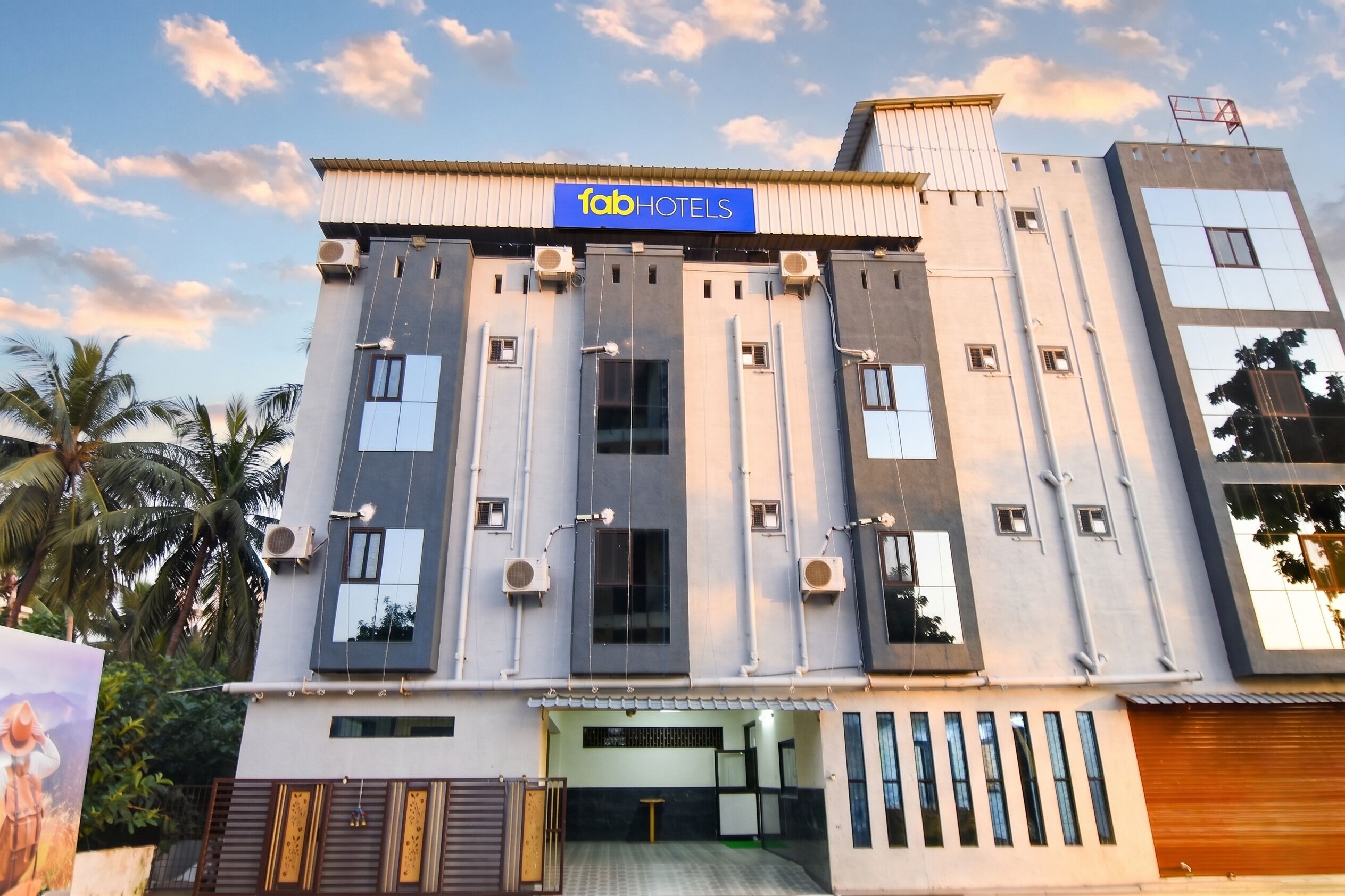 A modern building with a sign reading 'fabHOTELS' and multiple air conditioning units.