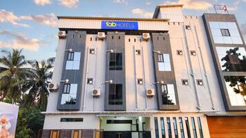 A modern building with a sign reading 'fabHOTELS' and multiple air conditioning units.