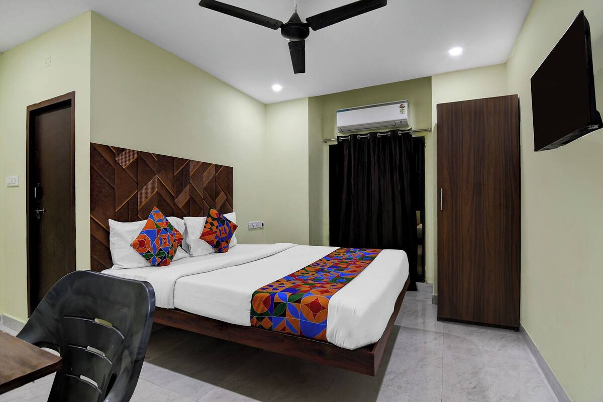 Ein Hotelzimmer mit einem Bett, einem Deckenventilator, einer Klimaanlage, einem Fernseher und einem Kleiderschrank.