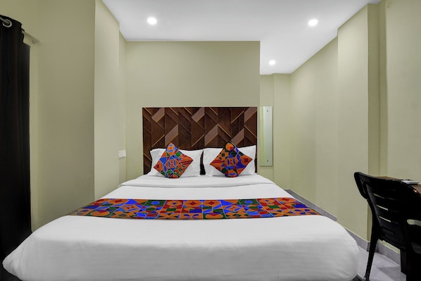 A hotel room with a bed, a headboard with a geometric pattern, and a chair.