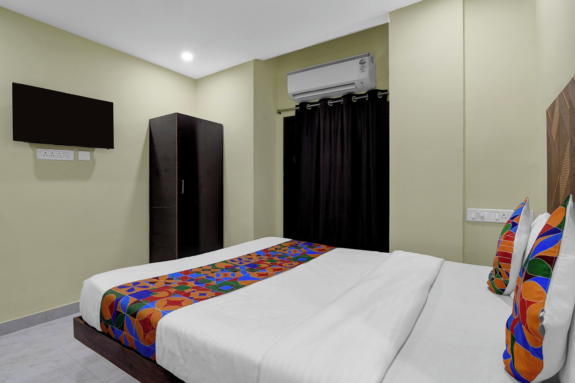 Une chambre d’hôtel équipée d’un lit, d’une armoire, d’un téléviseur à écran plat, d’un climatiseur et d’un rideau.