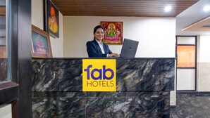 A hotel reception desk with a marble counter, a laptop, and framed artwork on the wall. - FabHotel Star Light B - Nr. Rushikonda (Visakhapatnam)