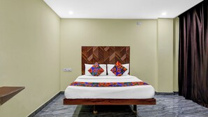 A hotel room with a bed, a headboard with a geometric pattern, a marble floor, and a dark curtain. - FabHotel Star Light B - Nr. Rushikonda (Visakhapatnam)