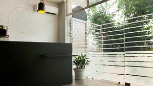 En moderne reception med et stort vindue, en potteplante og en væg med runde mønstre.