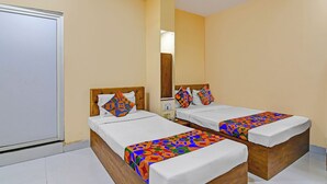 A hotel room with two beds, each with a colorful geometric-patterned bedspread and matching pillows. - Via Philips (Kolkata)