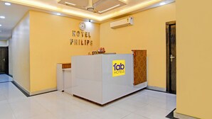 A hotel reception desk with a clock, air conditioning unit, and a sign for 'fab hotels'. - Via Philips (Kolkata)