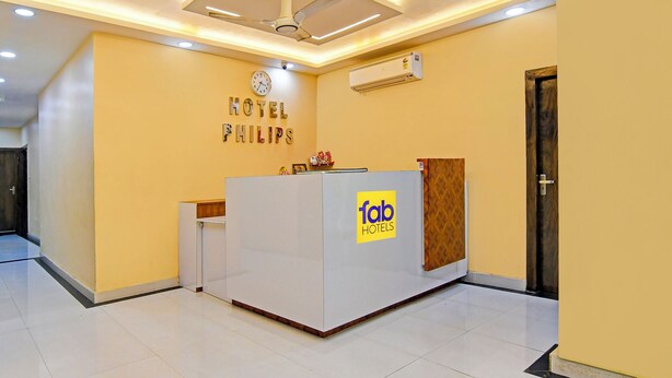 A hotel reception desk with a clock, air conditioning unit, and a sign for 'fab hotels'. - Via Philips (Kolkata)