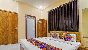 A hotel room with a bed, a nightstand, a wardrobe, and a door. - Via Philips (Kolkata)
