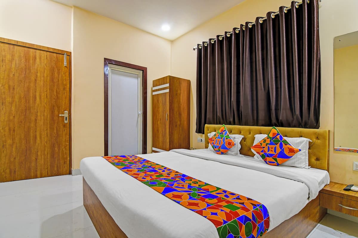 Une chambre d’hôtel avec un lit, une table de chevet, une armoire et une porte.