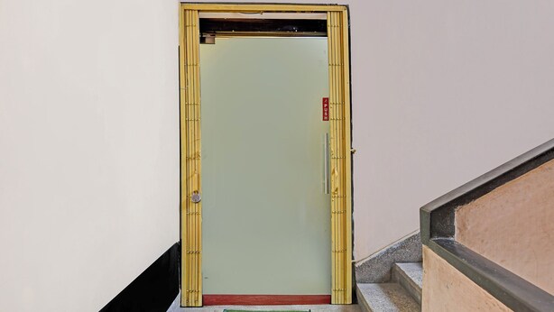 A door with a push sign, a green mat, and a staircase with a black handrail. - Via Philips (Kolkata)