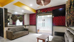 A modern living room with a grey sofa, a wooden coffee table, and a ceiling fan. - Fabexpress Sagar Residency (Panvel)