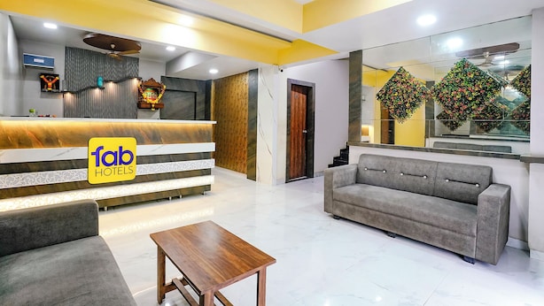 A hotel reception area with a marble reception desk, a sofa, and a coffee table. - Fabexpress Sagar Residency (Panvel)