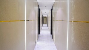 Un corridoio moderno di un hotel, con un lungo percorso rettilineo, pareti chiare e pavimento lucido.