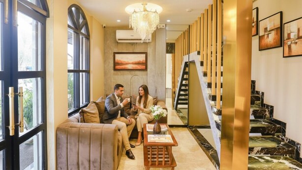 Una hall d'albergo moderna con un'area salotto, una scalinata e un lampadario.