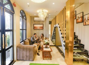 A modern hotel lobby with a seating area, a staircase, and a chandelier. - Fabhotel Dolphin Residency (Mumbai)
