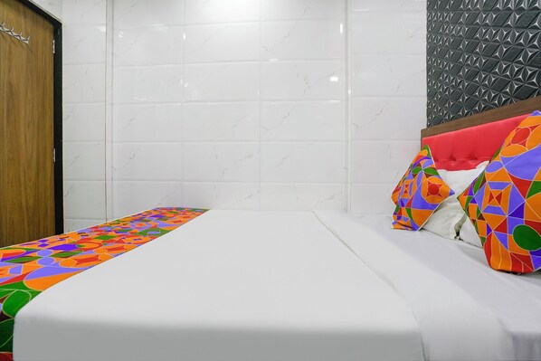 A hotel room with a bed, a wooden door, and a tiled wall.