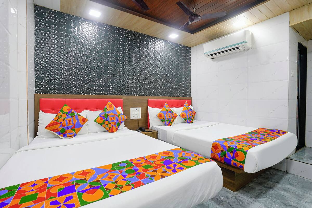 A hotel room with two beds, a red headboard, and a patterned wall.