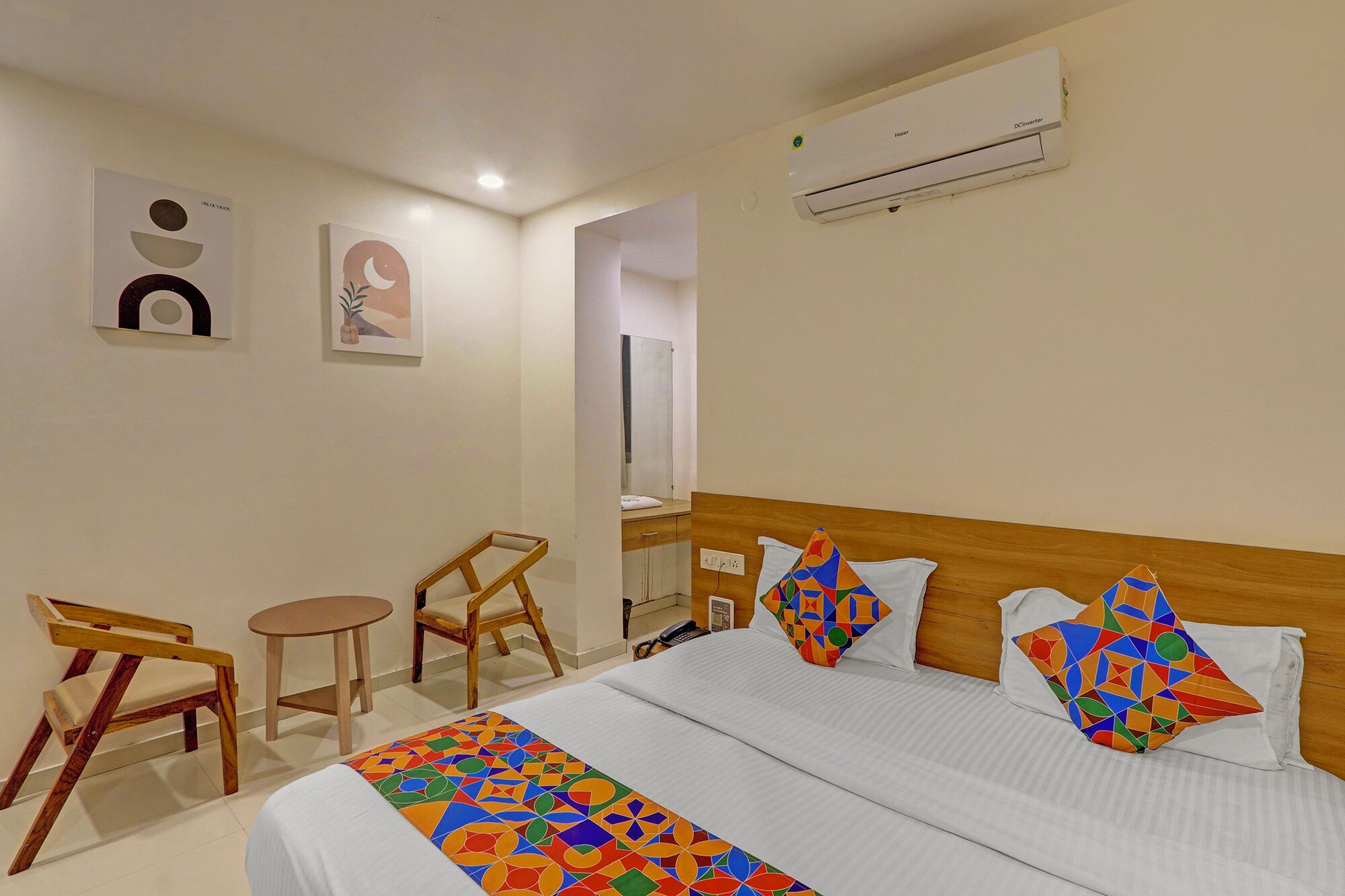 A hotel room with a bed, a desk, a chair, and a mirror.