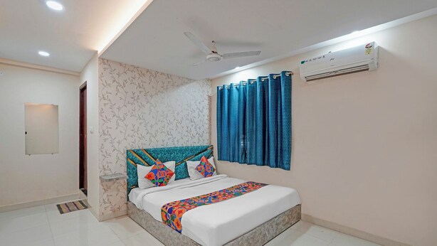 A bedroom with a bed, a ceiling fan, an air conditioner, and a window with curtains. - Fabhotel Elite Inn I (Indore)