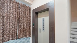 An elevator with a control panel, a door with a window, and a patterned curtain. - Fabhotel Elite Inn I (Indore)