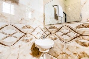 A bathroom with a white sink, marble-patterned walls, and a large mirror. - Fabhotel Nova Rooms (Surat)
