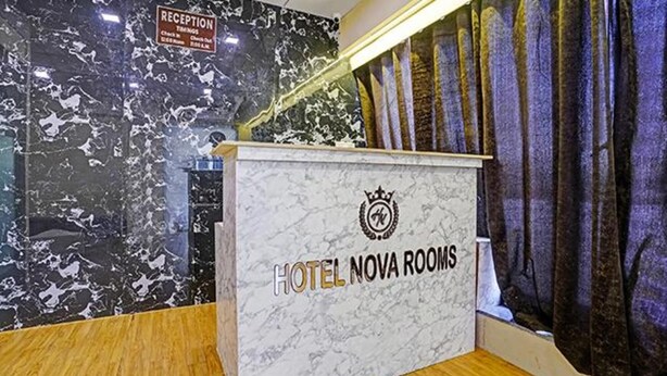 A reception desk with a marble wall and a sign that reads "HOTEL NOVA ROOMS". - Fabhotel Nova Rooms (Surat)