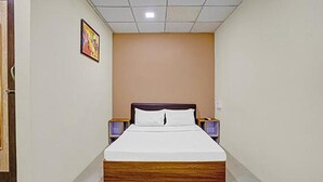 A hotel room with a single bed, a wooden headboard, two bedside tables, and a framed picture on the wall. - Fabhotel Nova Rooms (Surat)