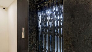 A modern elevator with a metallic, geometric design and a control panel on the left.