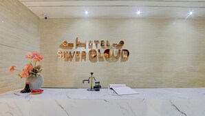 A reception desk with a marble surface, a vase of flowers, and a sign reading "HOTEL SILVER CLOUD".