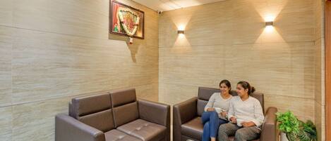 A modern waiting area with two brown leather sofas, a glass coffee table, and a framed picture on the wall.