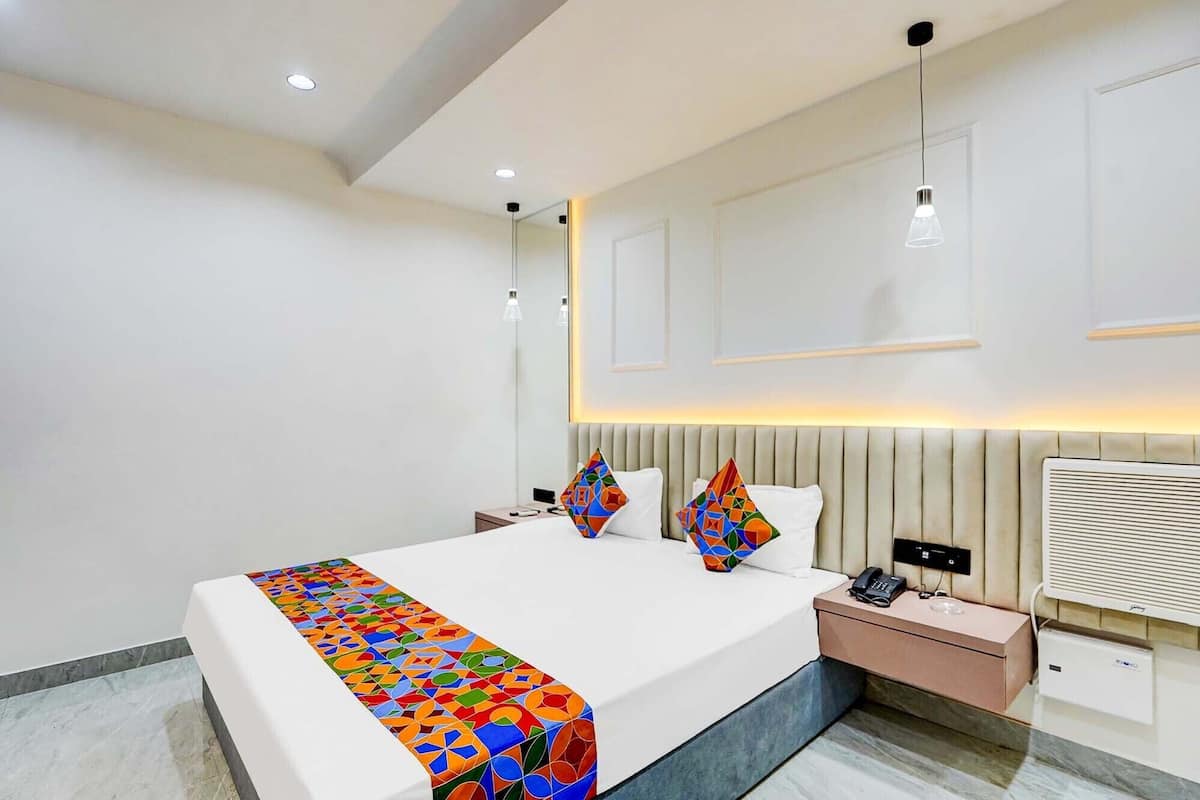 Une chambre d’hôtel moderne dotée d’un grand lit, de tables de chevet, d’une petite table et d’un radiateur intégré.
