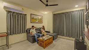 A living room with a sofa, a coffee table, and a ceiling fan. - Fabhotel Virat Elite (Hyderabad)