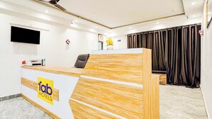 A reception desk with a logo, a flat-screen TV, and a chair. - Fabhotel Golden Inn (Noida)