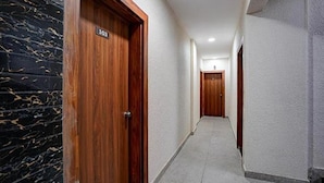 A hallway with a wooden door labeled "103" and a marble wall. - Fabhotel Seven Elite (Paud)