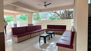 An outdoor seating area with a sofa and tables, a ceiling fan, and a view of greenery. - Fabhotel Seven Elite (Paud)