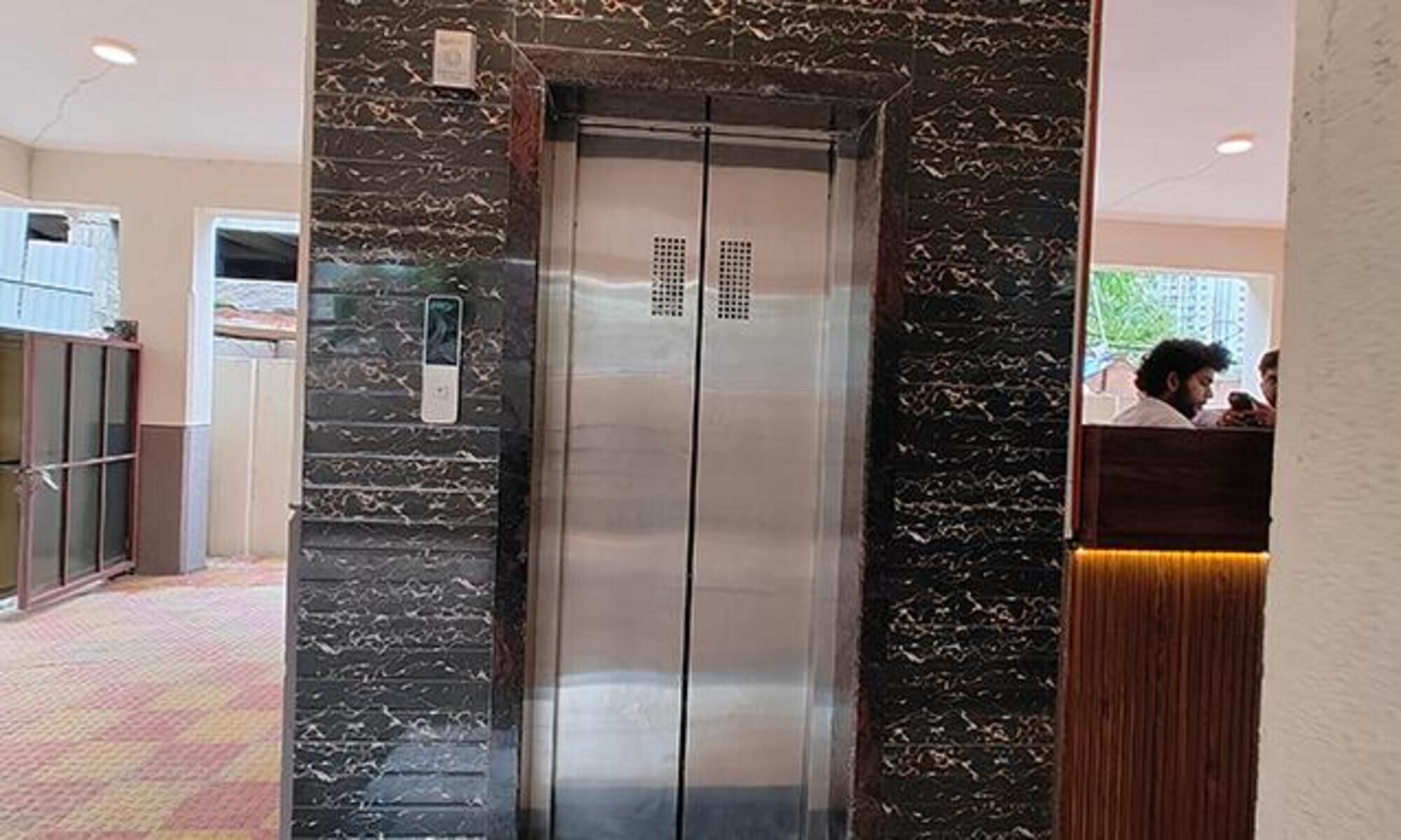 An elevator with a marble wall and a control panel.