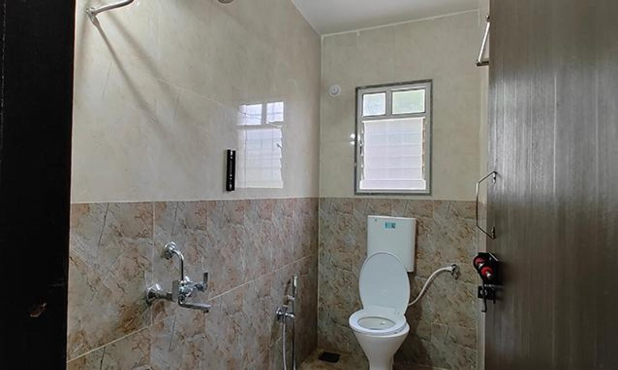 A bathroom with a toilet, a shower, and a window.
