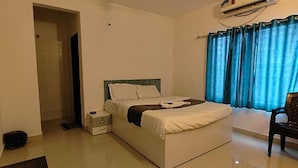 A hotel room with a bed, a bedside table, a chair, and a window with curtains. - Fabhotel Seven Elite (Paud)
